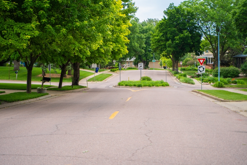 A photograph of Edgewood Rd in the Tuthill Park neighborhood. Dashed yellow lines to separate the the driving lanes are visible in the foreground, and a roundabout is visible in the background.